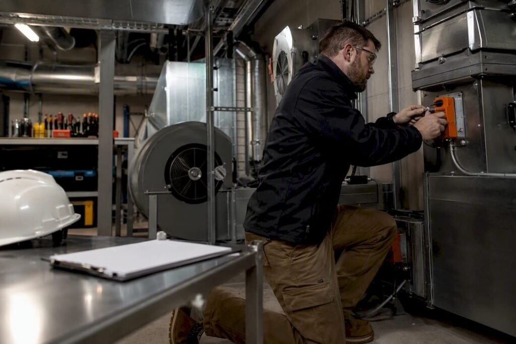 Technician inspecting smoke damper in mechanical room